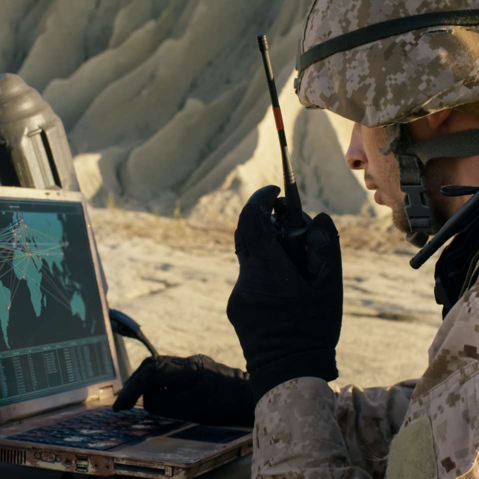 soldier using a hand-held radio whilst using a laptop